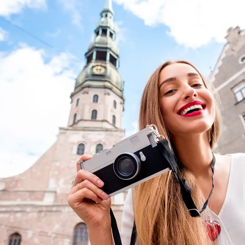 Young Female Photographer Smiling As She Snaps A Picture In Riga Old Town, Latvia